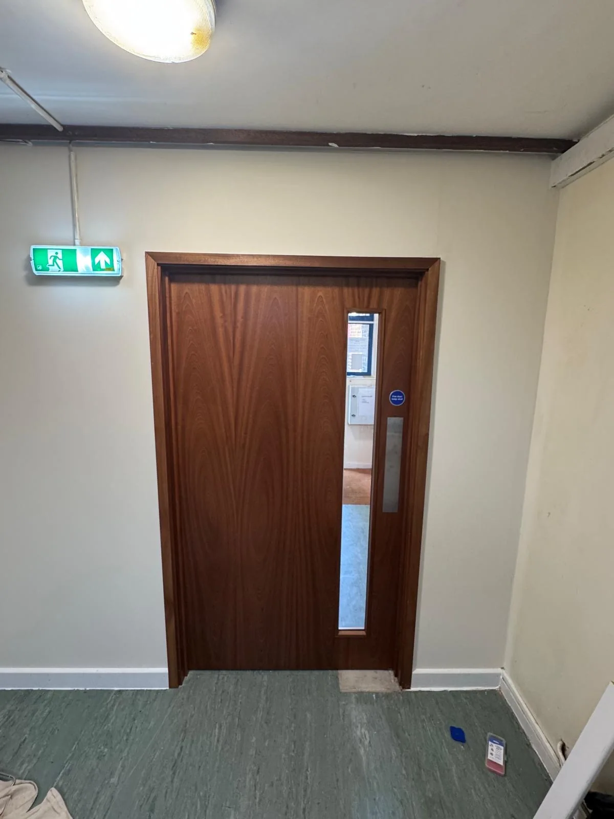 New timber communal fire door with narrow glazed vision panel, first side